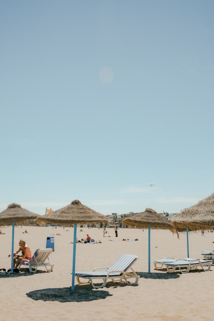 a sandy beach with lounge chairs and straw umbrellas