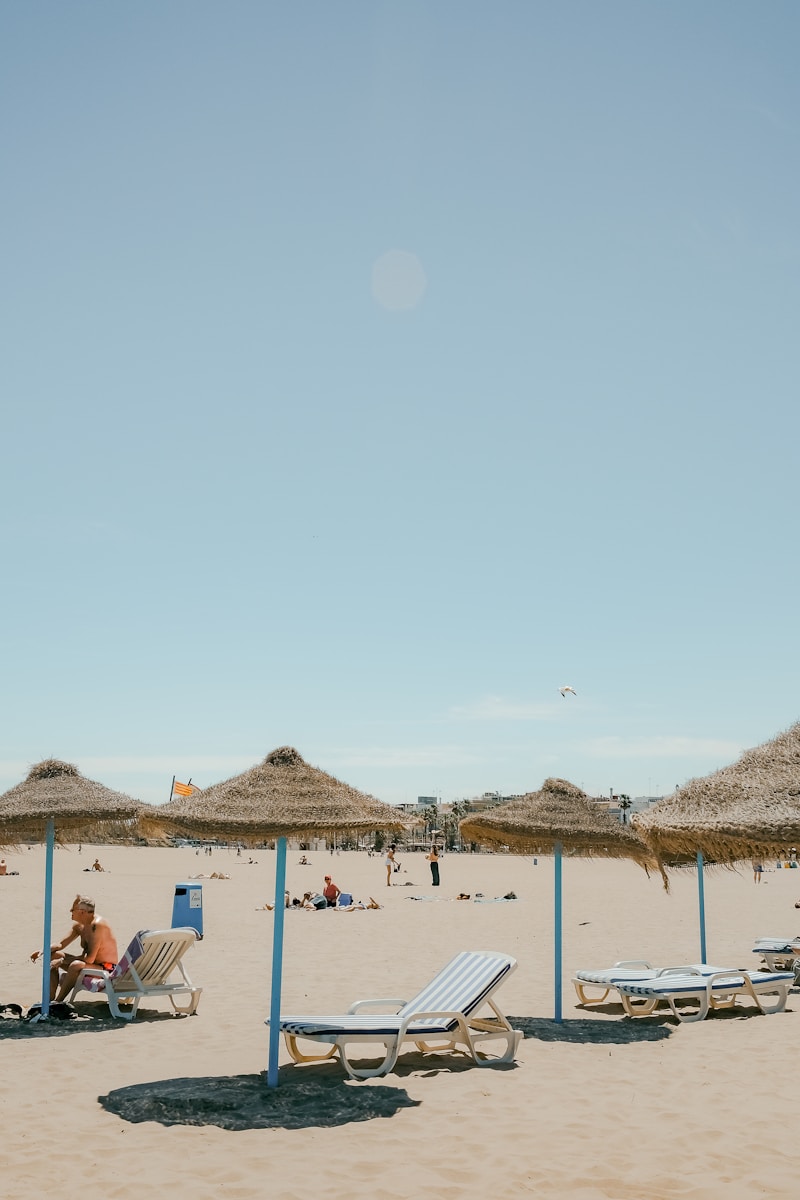 a sandy beach with lounge chairs and straw umbrellas